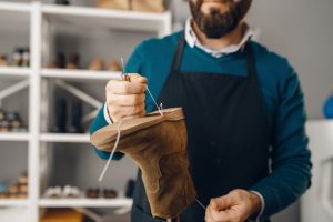 Shoemaker stitches the shoe, footwear repair